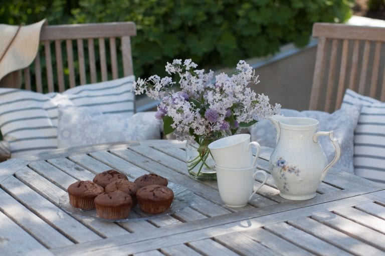 Fikapaus med chokladmuffins och lila syrener i vas.